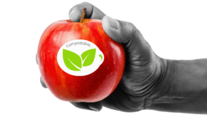 Hand holding a red apple with a fruit sticker on